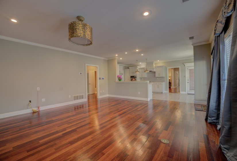 Unfurnished living room with crown molding and dark wood-type flooring