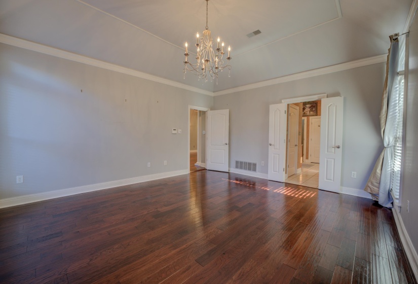 Unfurnished bedroom with crown molding, dark hardwood / wood-style flooring, and an inviting chandelier