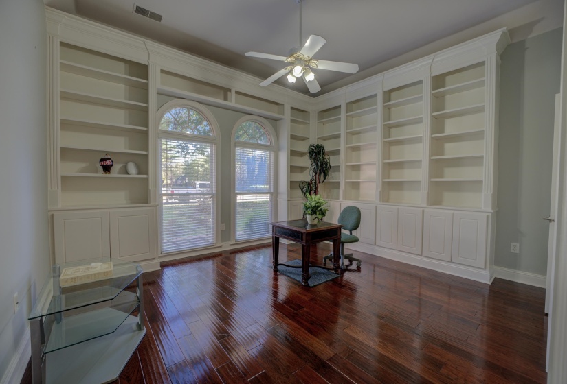 Office space featuring built in shelves, ceiling fan, and dark hardwood / wood-style flooring