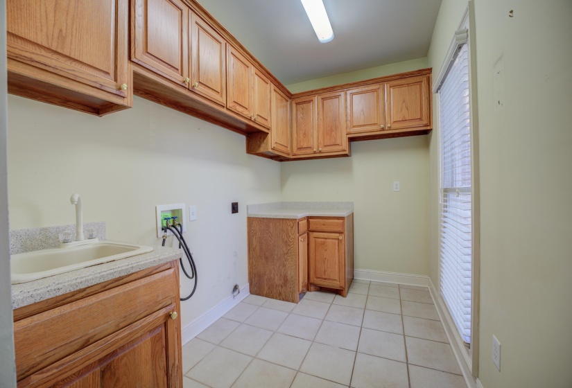 Washroom with hookup for a washing machine, cabinets, sink, and a wealth of natural light