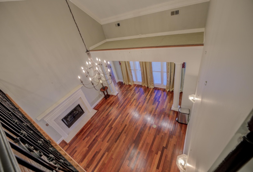 Living room featuring wood-type flooring, an inviting chandelier, and crown molding