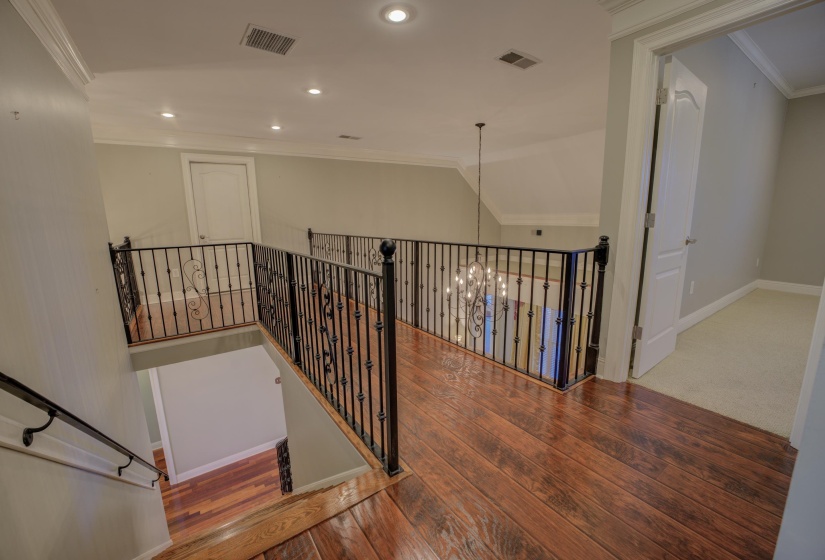 Staircase with hardwood / wood-style floors, an inviting chandelier, and ornamental molding