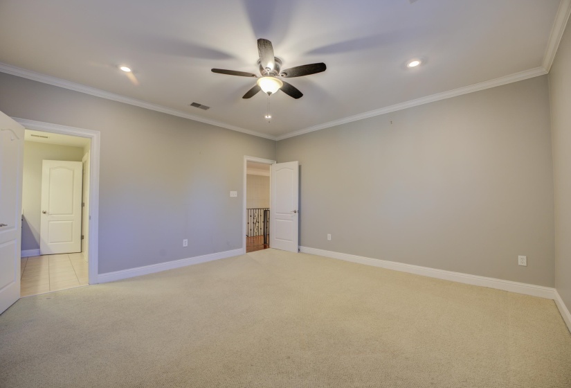 Unfurnished bedroom with ceiling fan, light colored carpet, and crown molding