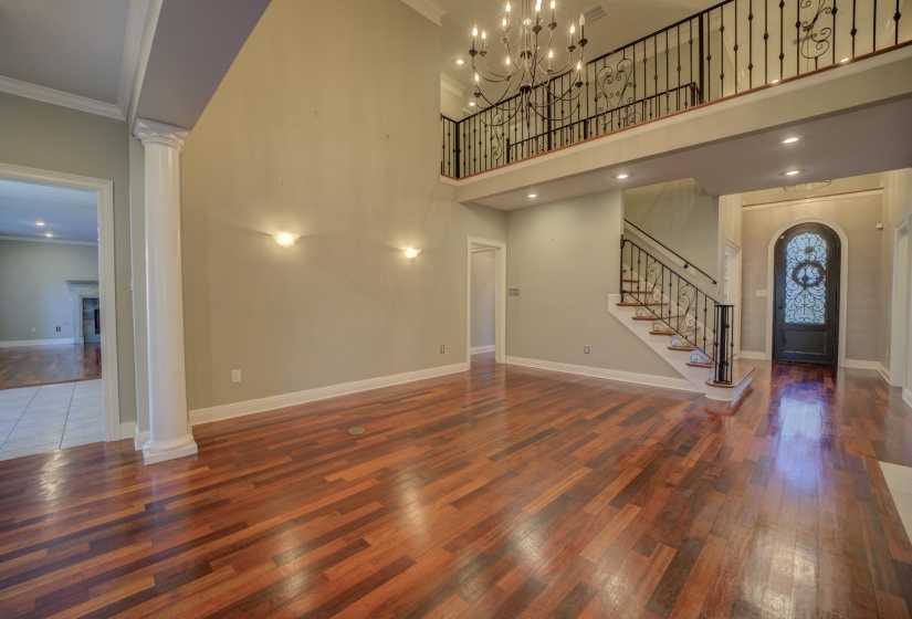 Entryway featuring ornamental molding, decorative columns, dark wood-type flooring, and a high ceiling