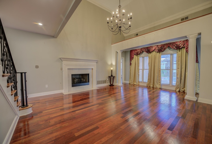 Unfurnished living room featuring a towering ceiling, dark hardwood / wood-style floors, an inviting chandelier, and crown molding