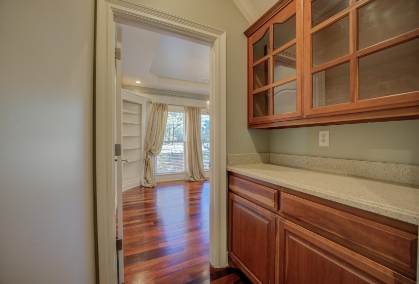 Bar featuring dark hardwood / wood-style floors, light stone counters, and ornamental molding