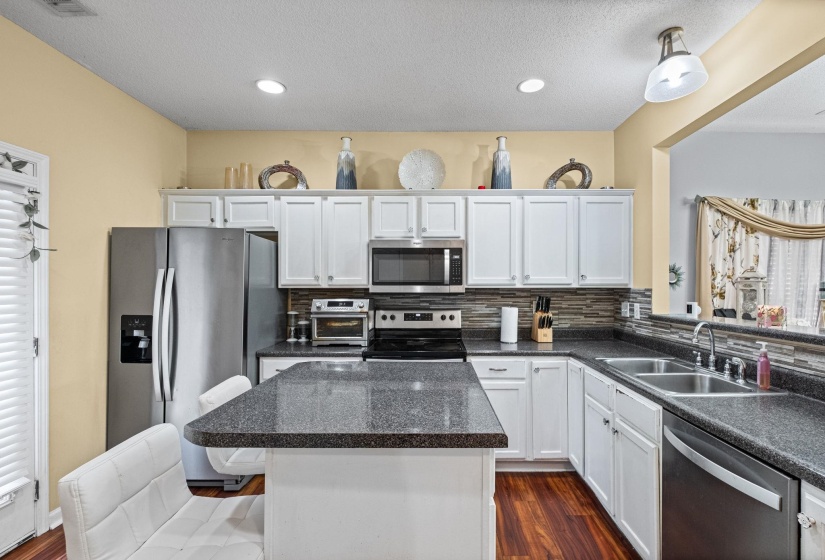 Modern kitchen featuring white cabinetry, dark speckled countertops, and a mosaic tile backsplash