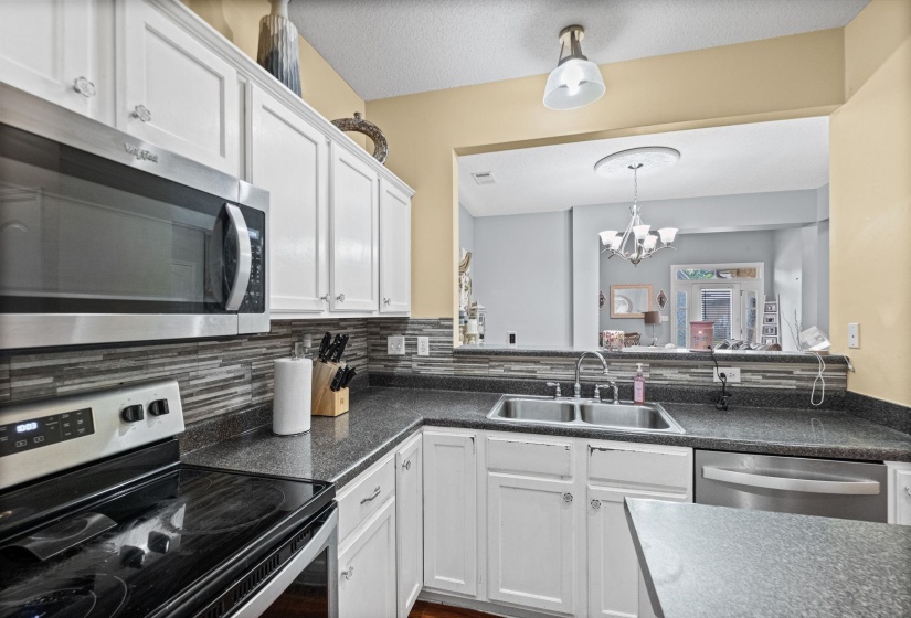 Kitchen featuring white cabinetry, dark speckled countertops, and a mosaic tile backsplash
