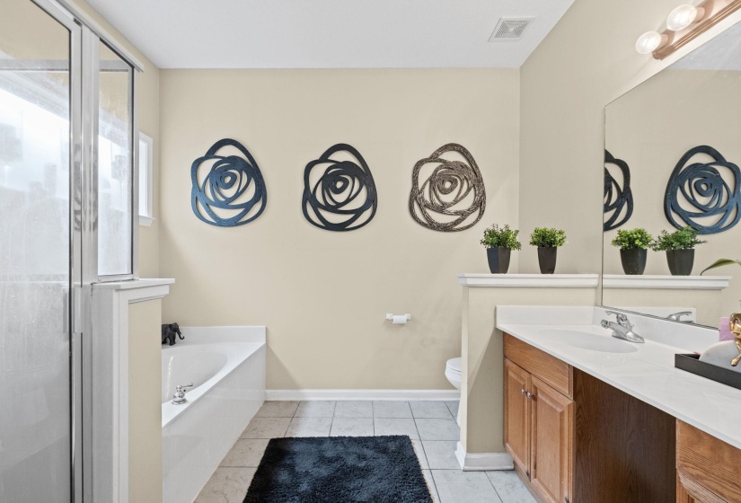 Bathroom featuring a glass-enclosed shower, built-in bathtub, and a wood-finish vanity with a single sink