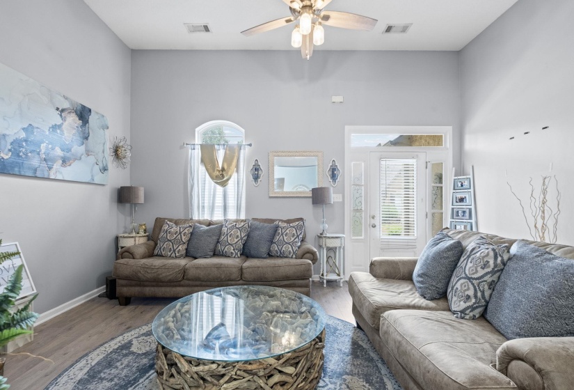Living area featuring vaulted ceilings, wood-finish flooring, and a ceiling fan with integrated lighting