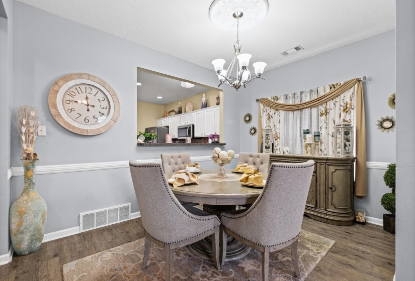 Formal dining space featuring wood-finish flooring, chair rail molding, and a chandelier with a decorative ceiling medallion