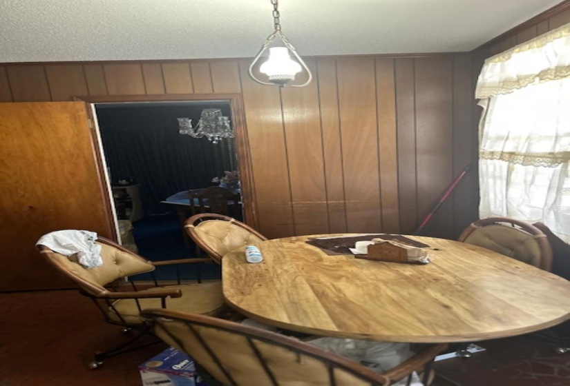 Wood paneling throughout this room, featuring a hanging light fixture and doorway