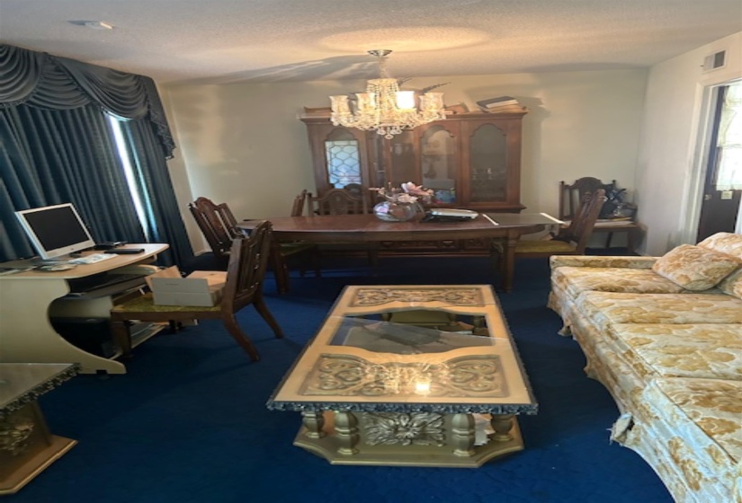 Dining area featuring a crystal chandelier, wood-finish flooring, and a large window with draped valance