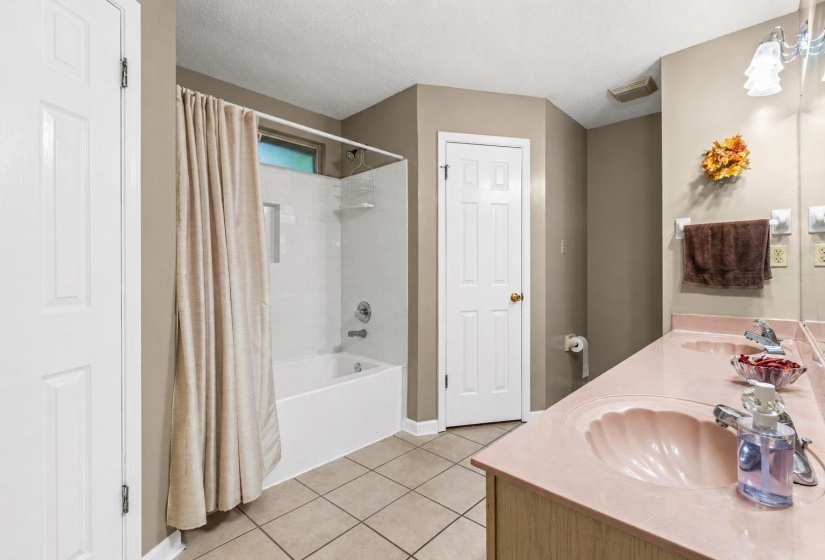 Bathroom featuring a new built-in tub and shower combination with white surround, dual vanity with integrated shell-motif sinks, and ceramic tile flooring