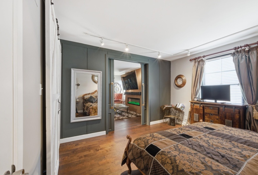 Room featuring wood-finish flooring, a sliding barn door, and a paneled accent wall