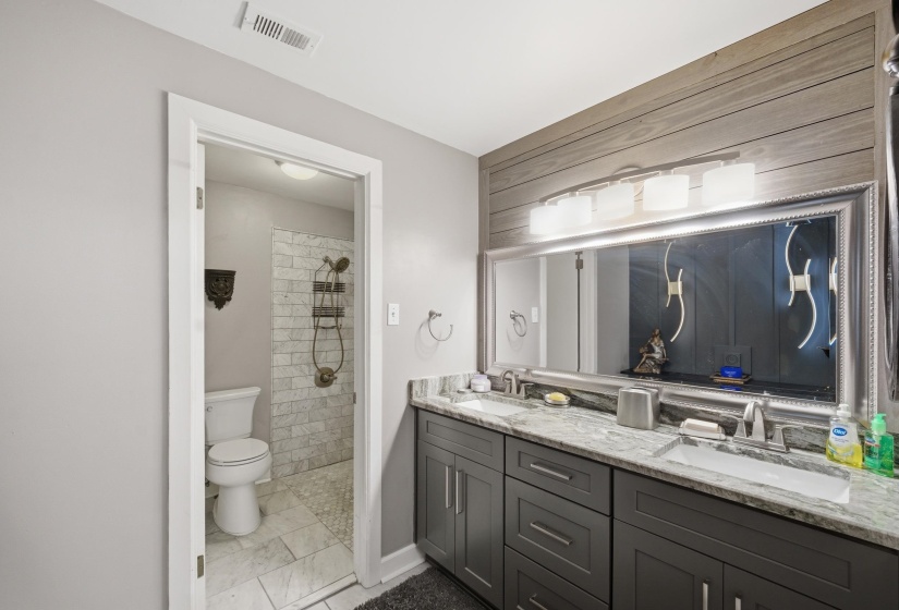 Double vanity with granite countertops, undermount sinks, and dark wood cabinetry