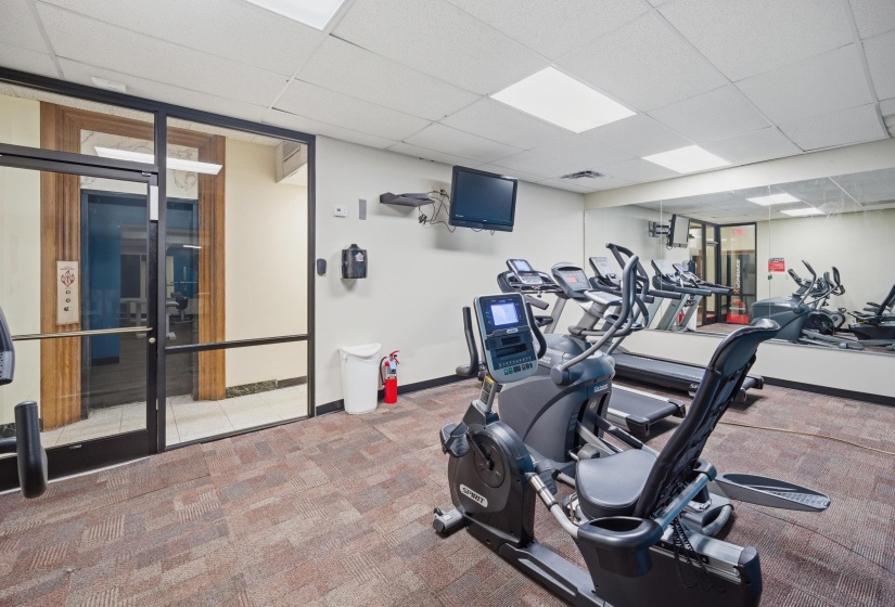 Fitness center featuring patterned carpet flooring, full-wall mirror, and recessed lighting