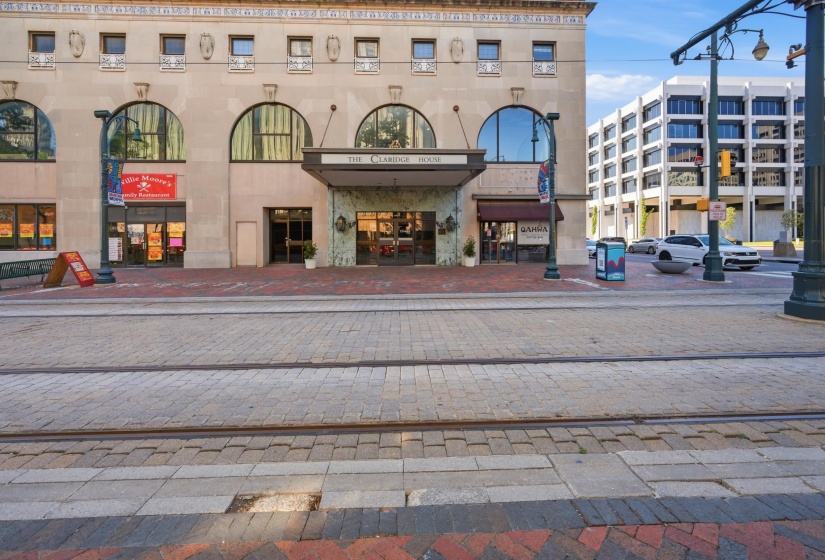 Historic building facade featuring arched windows, a covered entrance, ground-level retail spaces, and decorative architectural details