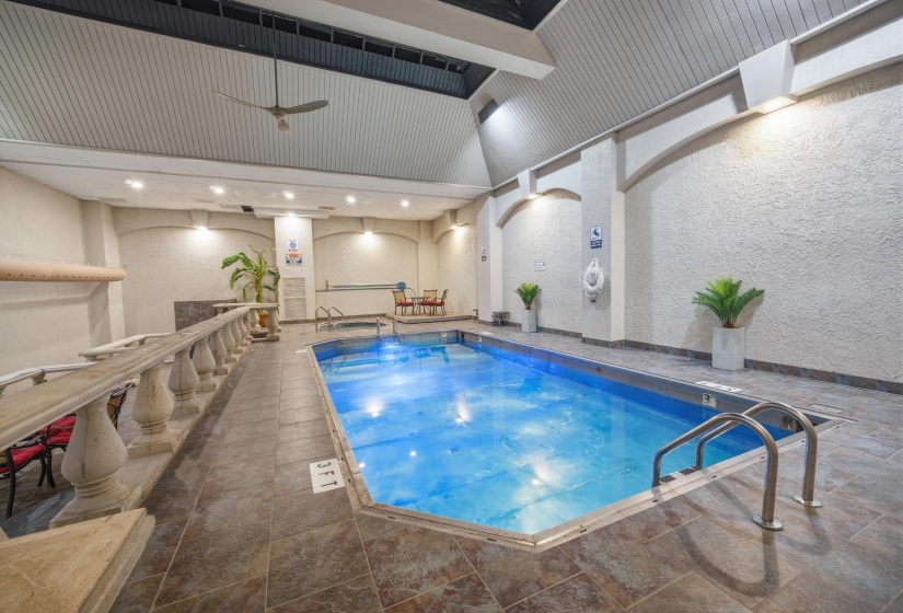 Indoor swimming pool with tile surround, vaulted ceiling, recessed lighting, and wall-mounted ceiling fan