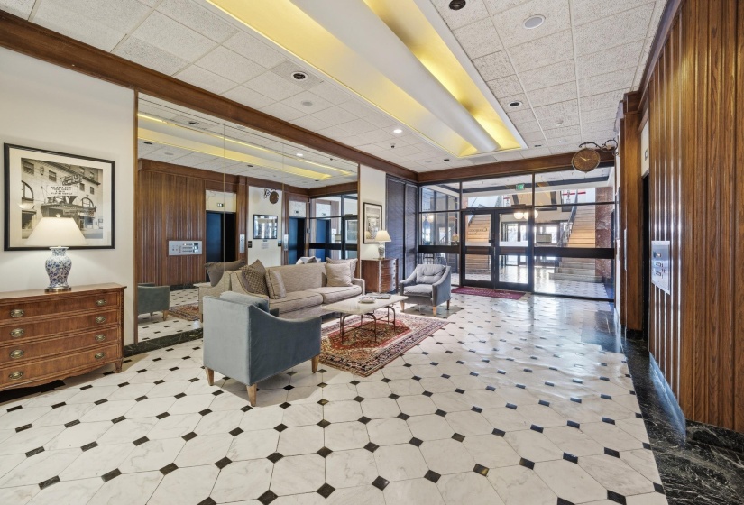 Lobby area featuring black and white patterned tile flooring, wood paneling, mirrored wall accents, and recessed ceiling lighting