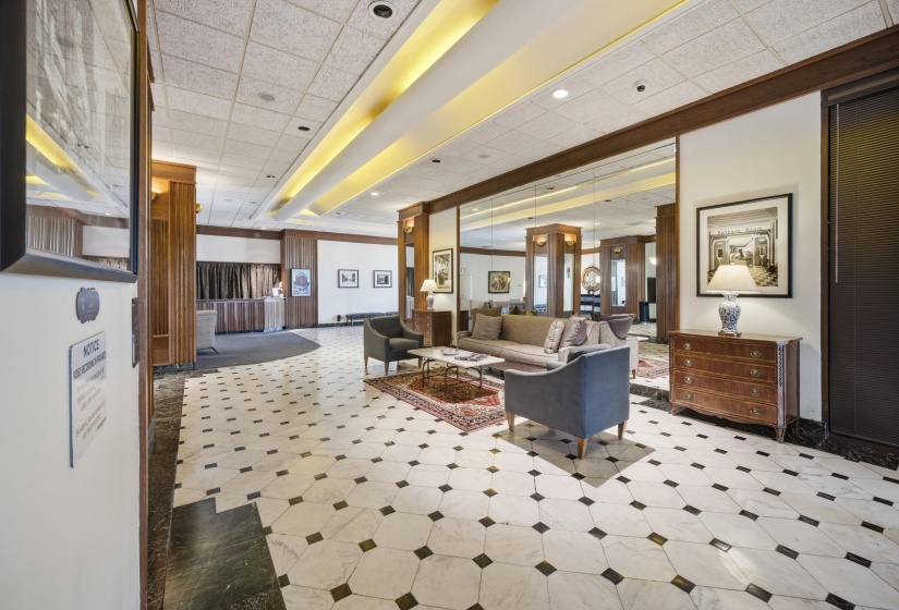 Spacious lobby area featuring patterned black and white tile flooring, wood paneling, recessed lighting, and wall-mounted mirrors