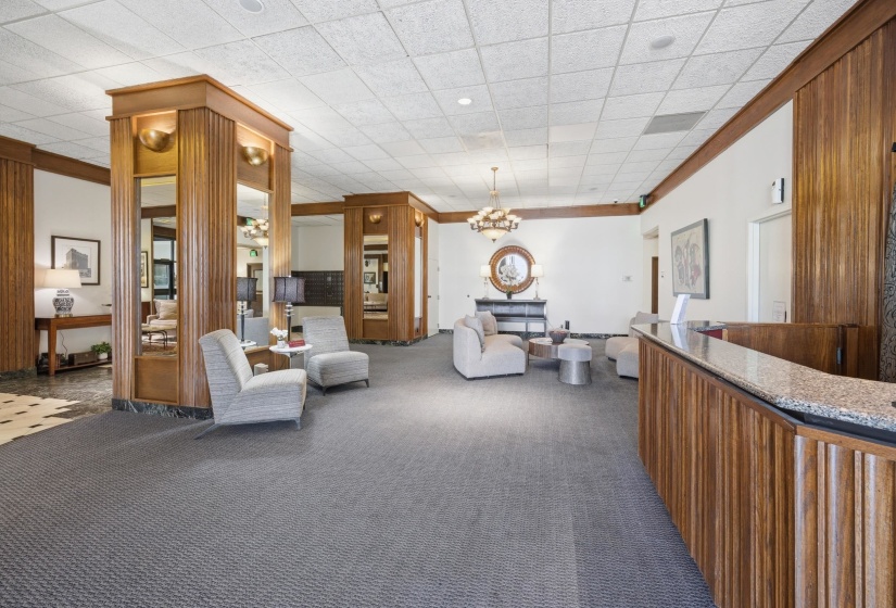Building lobby featuring a reception desk with stone countertop, wood-paneled walls with vertical fluting, recessed lighting, and patterned carpet flooring