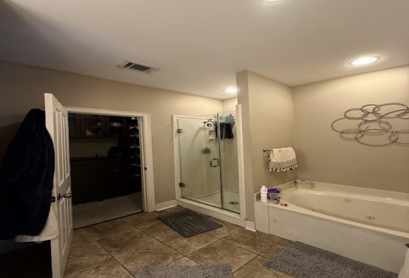 Bathroom featuring a spacious closet, a stall shower, a bath, dark tile patterned flooring, and recessed lighting