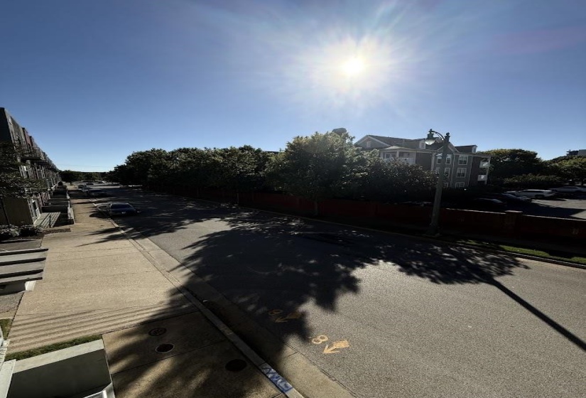 View of asphalt road featuring curbs and sidewalks