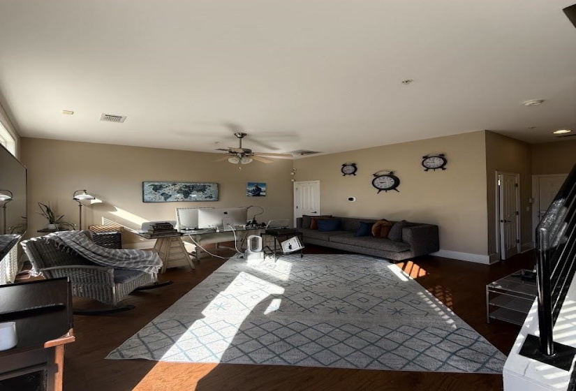 Living room featuring dark wood-type flooring and a ceiling fan