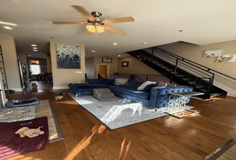 Living area featuring wood finished floors, stairs, a ceiling fan, and recessed lighting