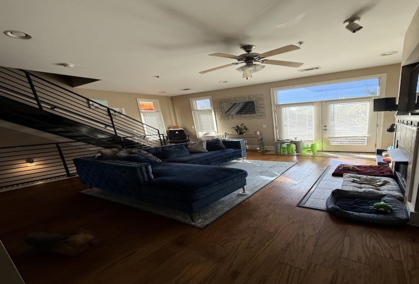 Living room featuring wood finished floors, healthy amount of natural light, stairs, and ceiling fan