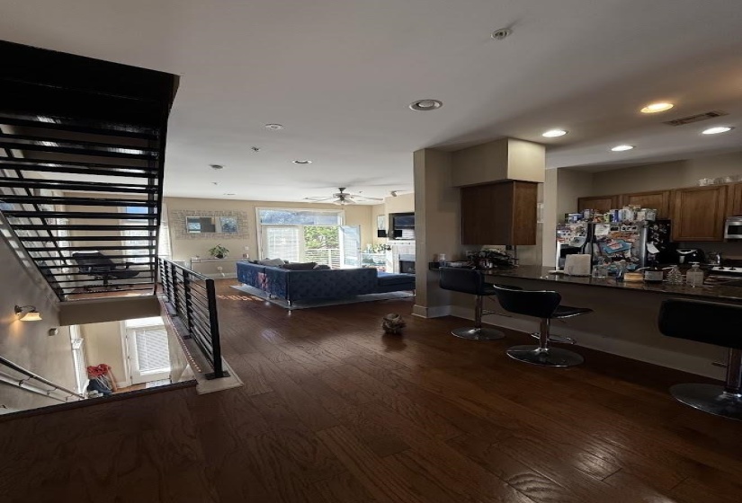 Kitchen featuring dark wood-style flooring, stainless steel fridge with ice dispenser, open floor plan, recessed lighting, and a breakfast bar area