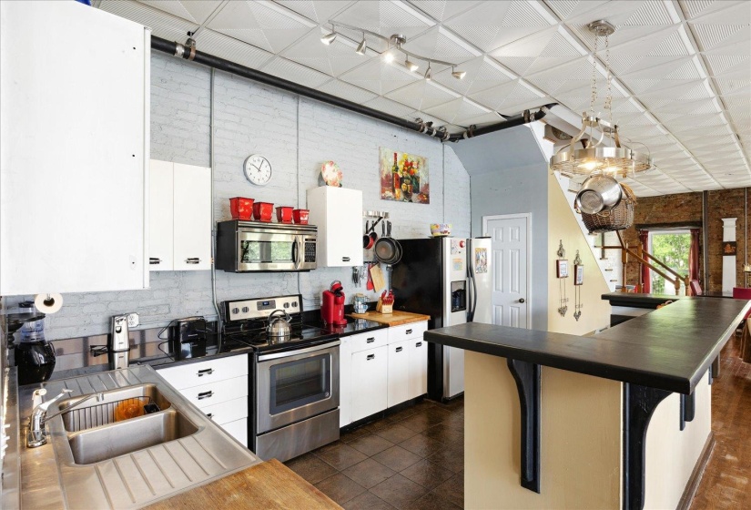 Kitchen with appliances with stainless steel finishes, dark countertops, backsplash, and white cabinets