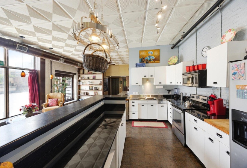 Kitchen with appliances with stainless steel finishes, white cabinetry, a sink, track lighting, and stainless steel counters