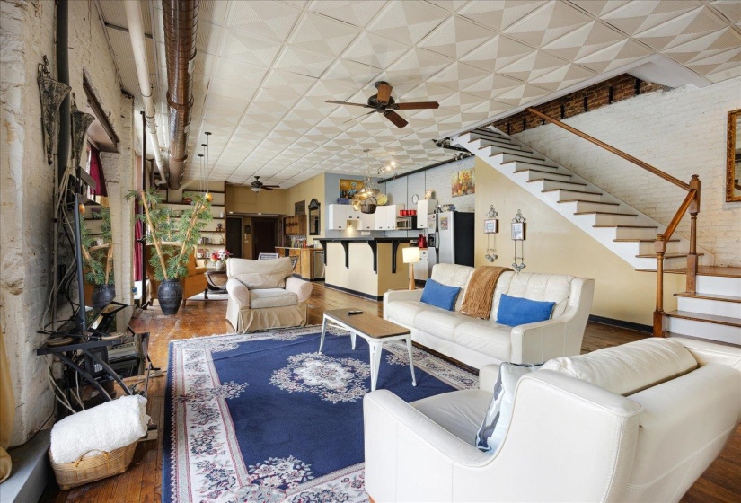 Living area with a ceiling fan, wood finished floors, stairs, and baseboards