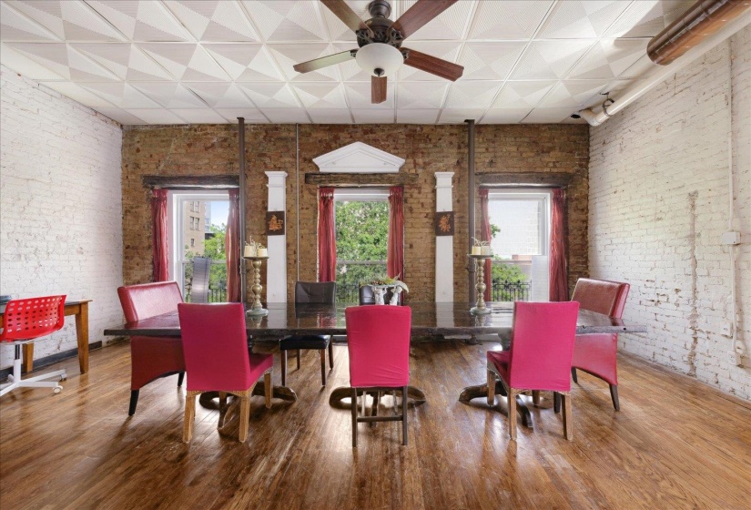 Dining room with healthy amount of natural light, brick wall, a ceiling fan, wood finished floors, and rail lighting