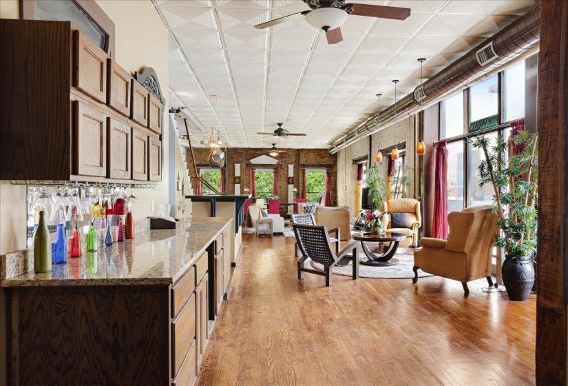 Kitchen featuring a ceiling fan, open floor plan, light wood-style floors, and light stone counters
