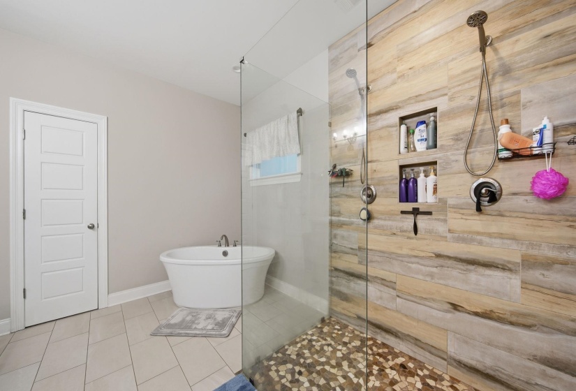 Modern walk-in shower featuring wood-look tile surround, dual shower heads, and built-in niches