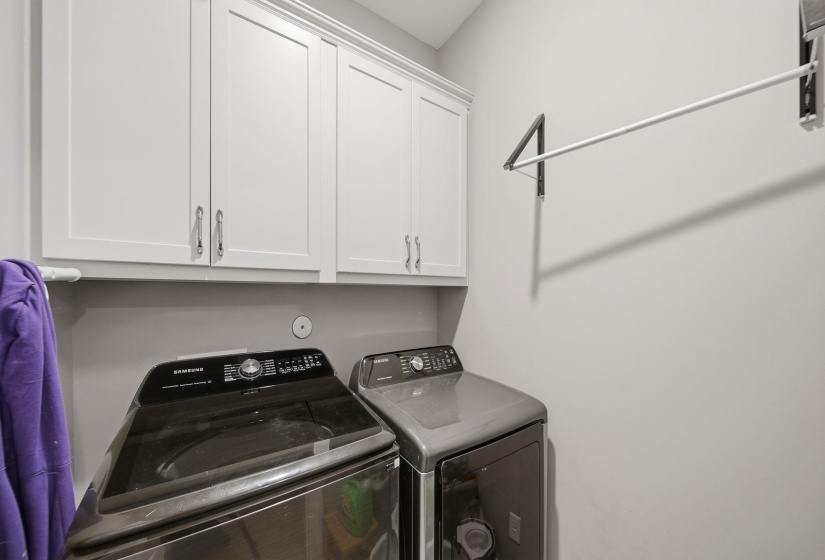 Laundry area featuring upper cabinetry with brushed nickel hardware and a wall-mounted drying rack