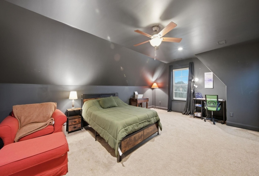 Carpeted room featuring a window, sloped ceilings, and a ceiling fan
