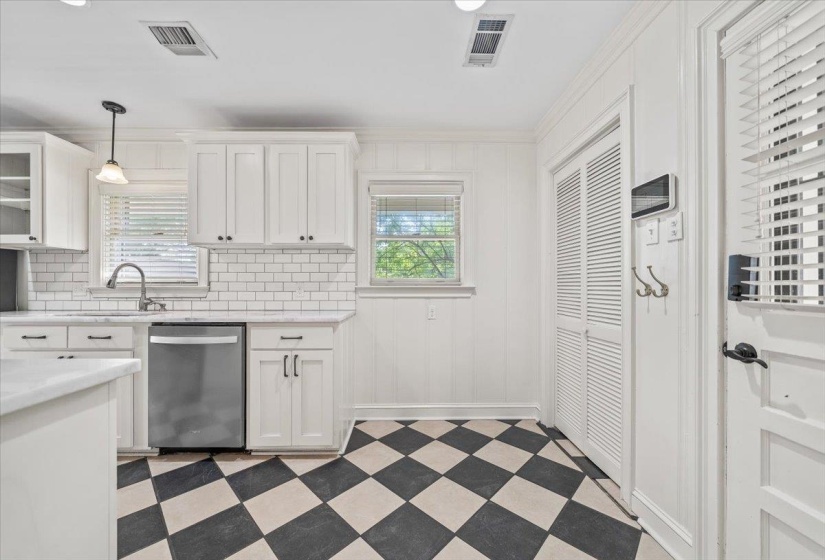 Kitchen featuring white shaker cabinetry, subway tile backsplash, stainless steel dishwasher, white countertops, and checkerboard floor tiling