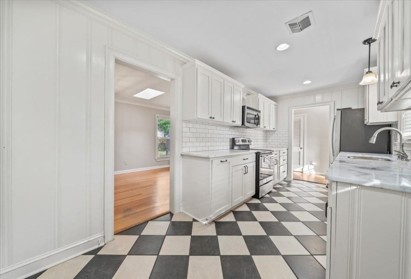 Kitchen featuring checkerboard flooring, white shaker cabinetry, subway tile backsplash, stainless steel appliances, and a light-toned countertop