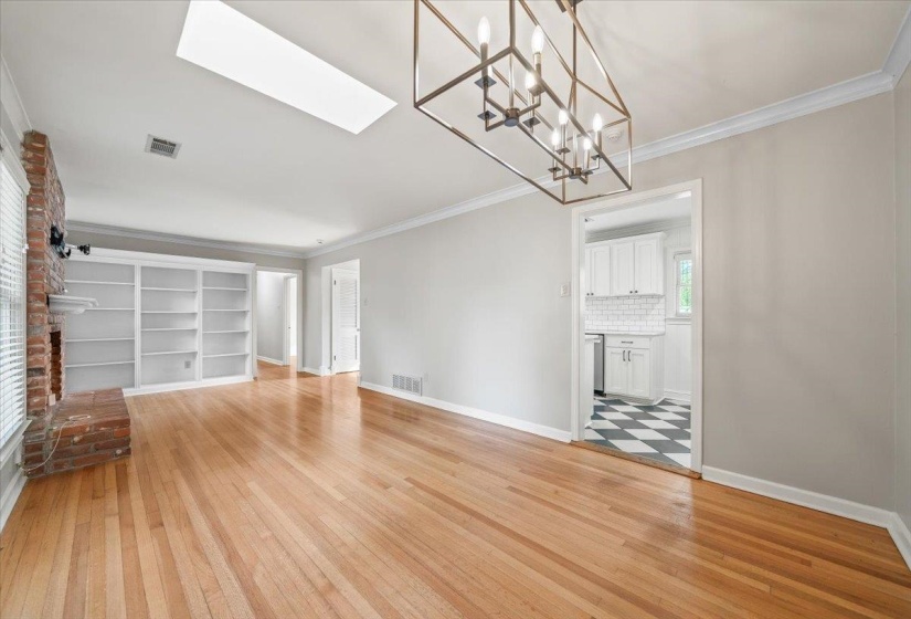 Spacious living area featuring wood-finish flooring, a brick fireplace, and built-in shelving