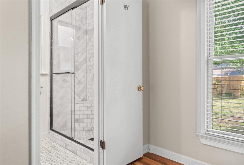 Shower enclosure with clear glass doors and black trim, featuring a white herringbone tile pattern on the walls