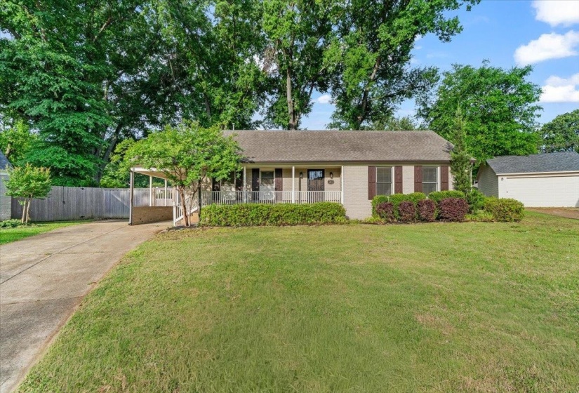 Single-story residence featuring a light-colored brick exterior, dark brown shutters, and an attached carport