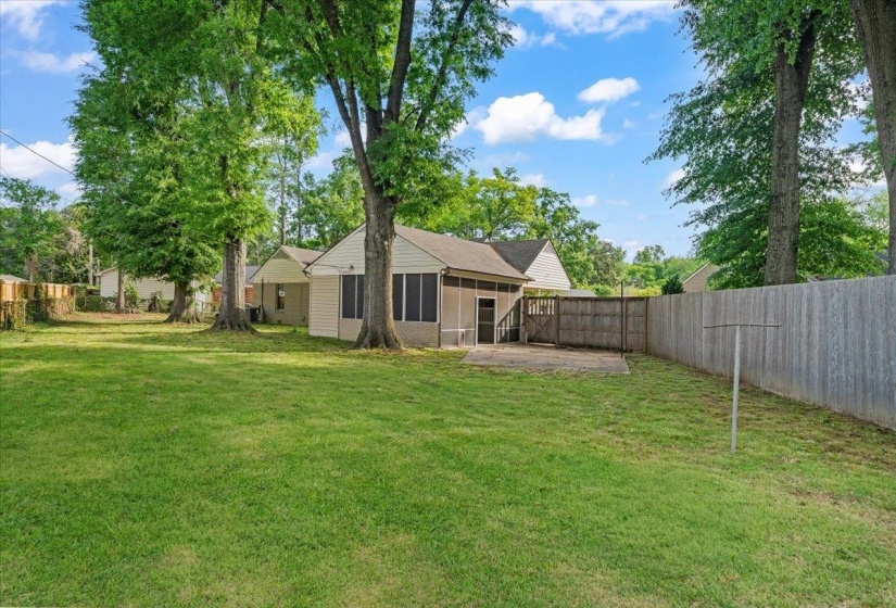 Generous backyard featuring mature trees, a screened-in porch, and a concrete patio