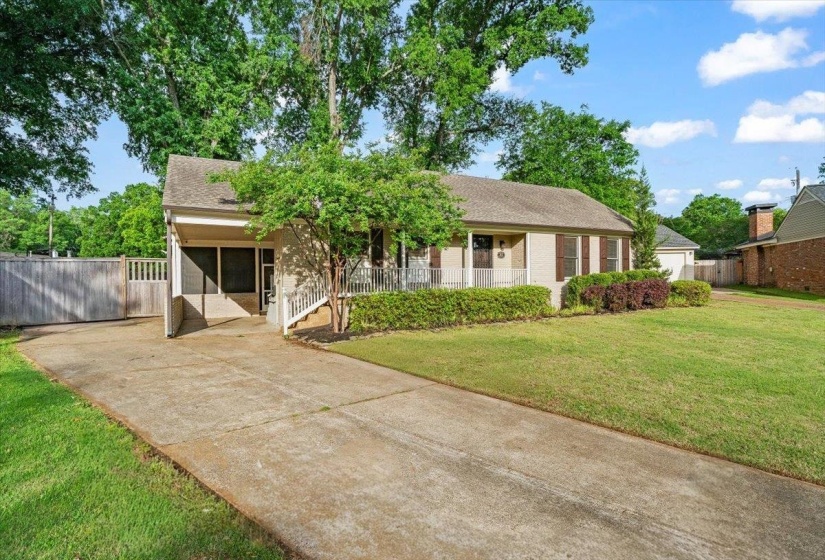 Ranch-style residence featuring a broad front lawn with established landscaping, an extended concrete driveway, and a covered carport