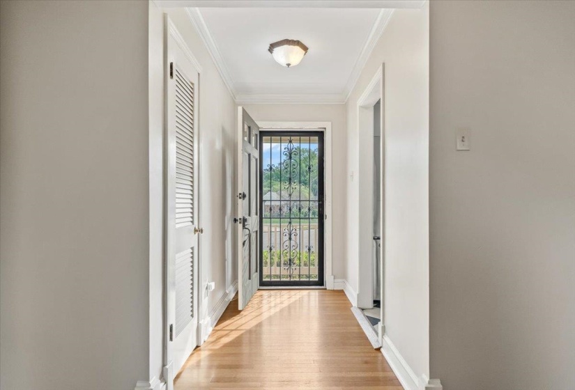 Foyer featuring hardwood flooring, white baseboards, crown molding, and a decorative ceiling light fixture