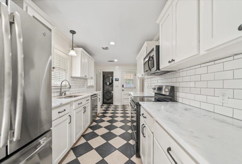 Galley kitchen featuring a checkerboard floor, white shaker cabinetry, stainless steel appliances, white subway tile backsplash, and light-toned countertops