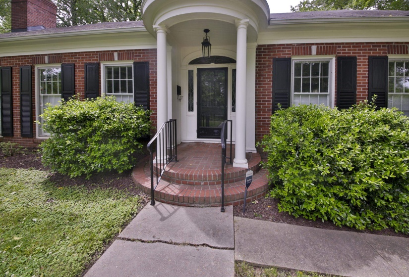Brick exterior with a covered entry featuring white columns and a black front door